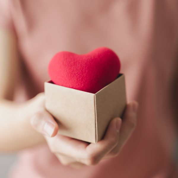 Woman holding giftbox with red heart, love, health insurance, donation, happy charity volunteer, world mental health day, world heart day, valentine's day